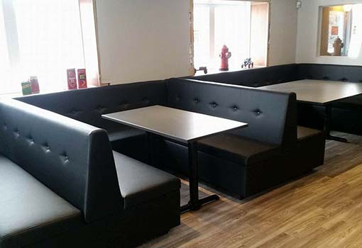 Trois banquettes en cuir noir avec tables dans un restaurant